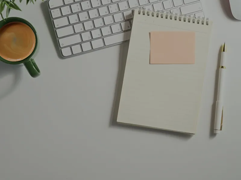 Birou văzut de sus, cu tastatură, carnet și cafea