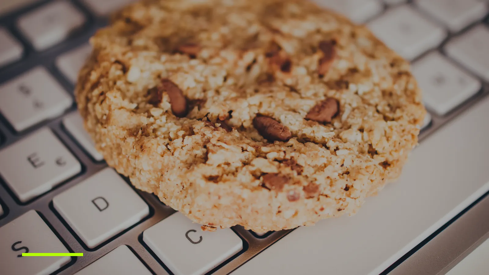 A cookie resting on a laptop keyboard, a nod to website cookies and consent banners