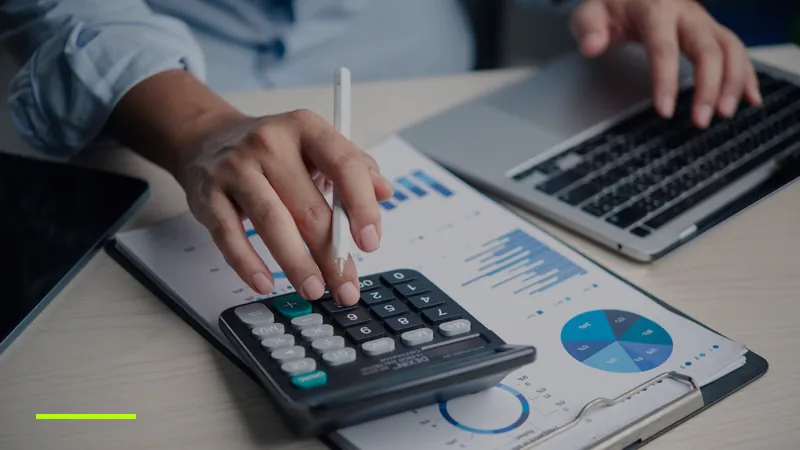Analist care calculează ROAS-ul minim pe un raport de buget cu grafice, lângă un laptop