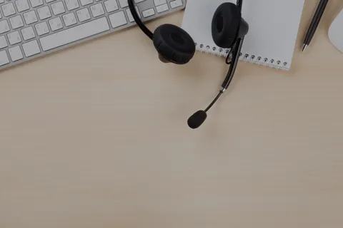 Căști cu microfon și carnet pe un birou